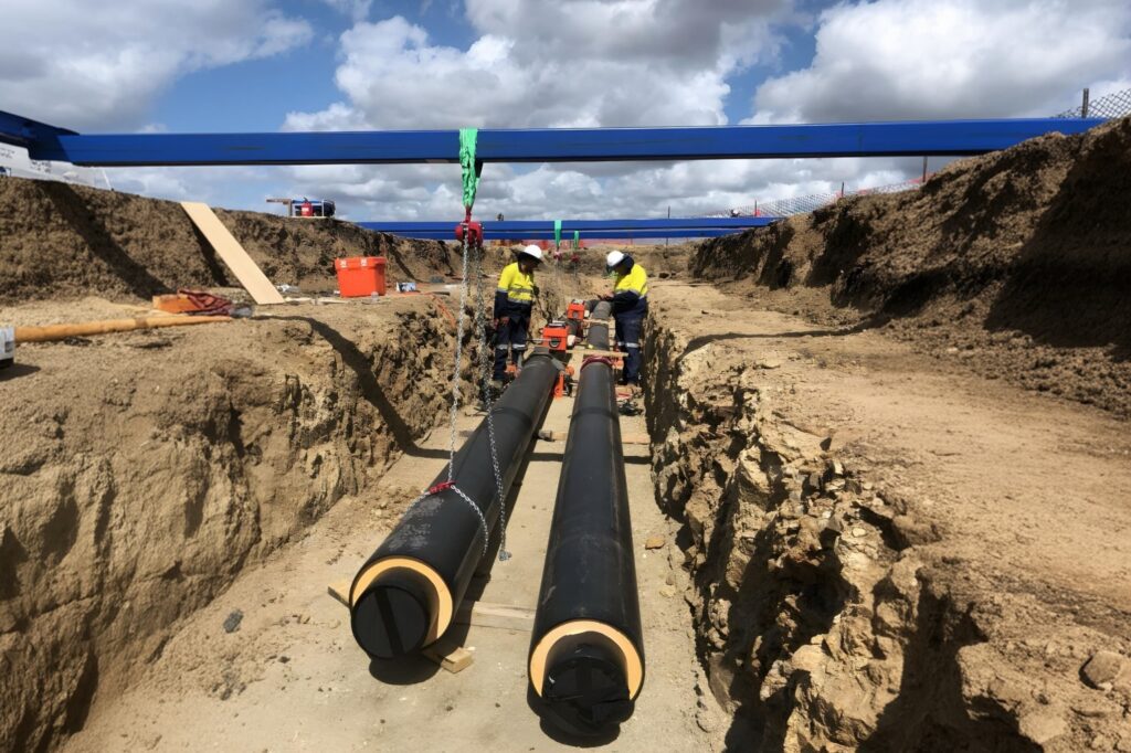 Installation of underground pre-insulated chilled water pipes for district cooling system.